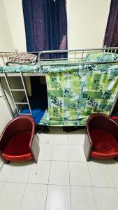 - deux chaises rouges assises à côté d'un lit superposé dans l'établissement SUNSHINE BOYS HOSTEL, à Dubaï