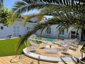 a patio with chairs and a table and a palm tree at Villa standing Biarritz in Biarritz