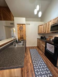 uma cozinha com armários de madeira e um lavatório em Cozy remodeled-condo near TUC Airport & Downtown em Tucson