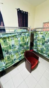 a red chair sitting in a room with bunk beds at SUNSHINE BOYS HOSTEL in Dubai