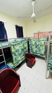 SUNSHINE BOYS HOSTEL في دبي: غرفة مليئة بالكثير من الأسرة بطابقين وكرسي احمر