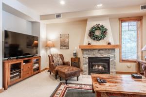 Una sala de estar con chimenea y televisión. en Upscale 4 Bed, 3 Bath at the Woodwinds with Amazing Mountain Views and Golf Course Access and private hot tub and garage sleeps 10, en Mammoth Lakes
