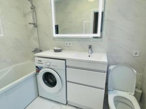 La salle de bains est pourvue d'un lave-linge et d'un lavabo. dans l'établissement На Куліша 3, сучасні апартаменти біля оперного, à Lviv