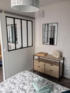 een slaapkamer met een bed en een dressoir met een spiegel bij Gîte aux Mille et un Détours in Pouillé