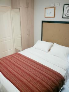 Un dormitorio con una gran cama blanca con una manta roja. en The Point Miraflores, Lima, en Lima