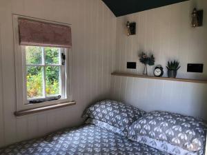 1 dormitorio con cama y ventana en The Old Vicarage Shepherd's Hut, en Stroud