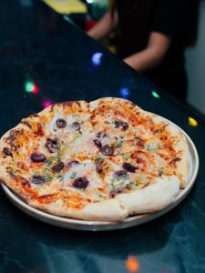 a pizza on a plate on a table at The Point Miraflores - Party Hostel in Lima