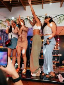 a group of women standing on a stage with their hands in the air at The Point Miraflores - Party Hostel in Lima