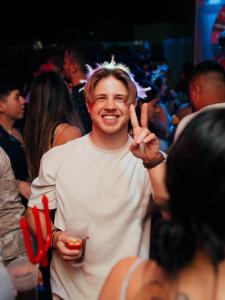 a man is making a peace sign with his hand at The Point Miraflores - Party Hostel in Lima