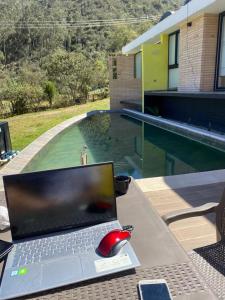 einen Laptop auf einem Tisch neben einem Pool in der Unterkunft Chalet Cerinza by Malaver in Cerinza