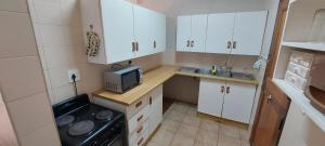 a small kitchen with white cabinets and a microwave at Cicada's Call Guest Cottage in Nelspruit