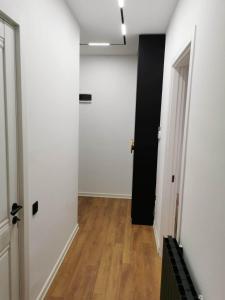 einen leeren Flur mit weißen Wänden und einer schwarzen Tür in der Unterkunft Tina Apartment N64 in Agaraki