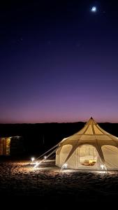 a white tent sitting in the sand at night at Infinity Camp in Bidiyah