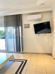uma sala de estar com uma televisão de ecrã plano na parede em Zerrin Hanım Apartments - 1 minute from Kleopatra Beach em Alanya