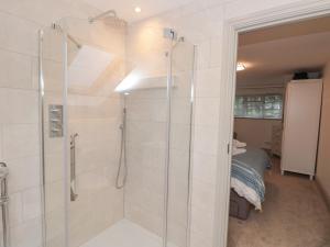 a bathroom with a walk in shower next to a bed at Raleigh House in Salcombe