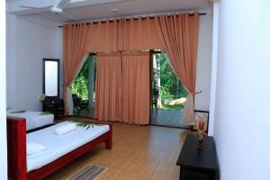 a bedroom with two beds and a large window at River Edge Yala in Tissamaharama