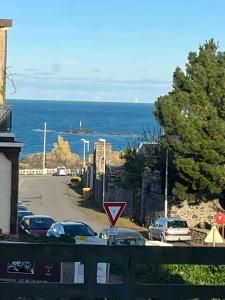 uma rua com carros estacionados numa estrada junto ao oceano em Appartement d'une chambre a Saint quay portrieux a 100 m de la plage avec vue sur la mer et terrasse amenagee em Saint-Quay-Portrieux