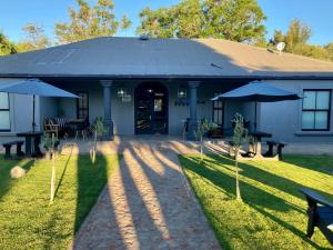 a building with tables and umbrellas in front of it at The Merino Guest House in Beaufort West