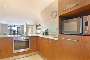 a kitchen with wooden cabinets and a microwave oven at Eden On The Bay 172 by HostAgents in Bloubergstrand