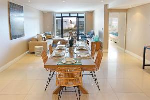 a dining room and living room with a table and chairs at Eden On The Bay 172 by HostAgents in Bloubergstrand