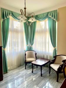 una sala de estar con cortinas y sillas verdes y una mesa. en Palace Inn en Jíloviště