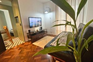 uma sala de estar com um sofá e uma planta em Lar da Abundância: Apartamento 3 Quartos no Leblon no Rio de Janeiro