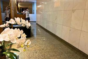 a lobby with white flowers and people walking in the lobby at Lar da Abundância: Apartamento 3 Quartos no Leblon in Rio de Janeiro