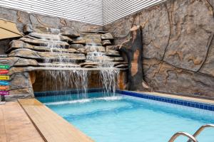 a swimming pool with a waterfall on a rock wall at Rede Andrade Amazônia in Manaus