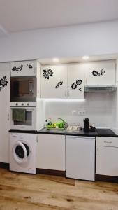 una cocina con armarios blancos, lavadora y fregadero en OTEIZA, en Madrid