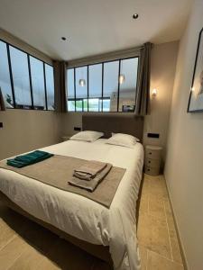 een slaapkamer met een groot wit bed en ramen bij La Remise-Gîte de charme 7 personnes avec jacuzzi in Saint-André-de-Sangonis