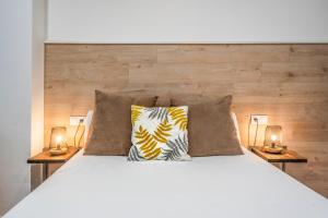 ein Schlafzimmer mit einem Bett mit zwei Lampen an Tischen in der Unterkunft AlohaMundi Montesión in Sevilla