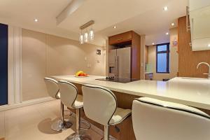 a kitchen with white chairs and a kitchen island at Eden On The Bay 108 by HostAgents in Bloubergstrand