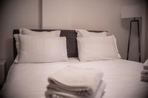 a bed with white sheets and pillows with towels on it at Maria's Premium Suite in Baia Mare