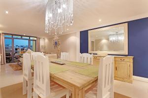 a dining room with a table and a chandelier at Eden On The Bay 108 by HostAgents in Bloubergstrand