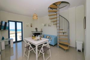 a living room with a table and a spiral staircase at Fanaraki villas 2 in Moúdhros