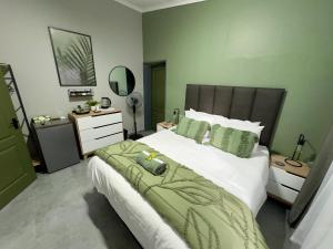 a bedroom with a bed with a green and white comforter at Wild Fig Rest Guest House in Polokwane