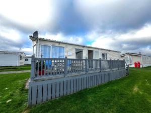 a house with a fence in front of a yard at Brilliant Caravan With Wifi And Decking Near Pakefield Beach Ref 68040cr in Lowestoft