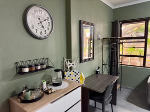 cocina con mesa y reloj en la pared en Wild Fig Rest Guest House, en Polokwane