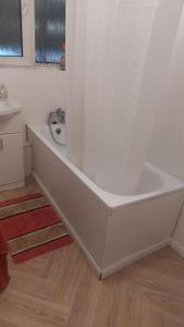 een badkamer met een wit bad en een wastafel bij Bethnal Green Guest House in Londen