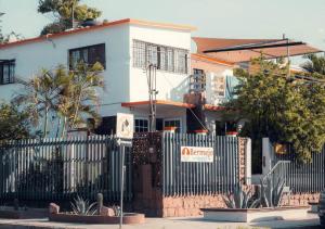 uma casa branca com uma cerca à frente. em Bermejo Hostel em La Paz
