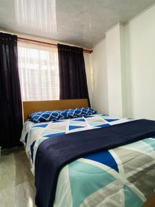 1 dormitorio con 1 cama con manta azul y blanca en Apartaestudio cerca al Aeropuerto en Bogotá