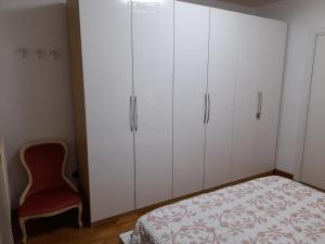 una camera da letto con armadi bianchi e una sedia rossa di INALPI ARENA ex Pala Alpitour-STADIO OLIMPICO - Luxury Apartment Virgilio - Santa Rita a Torino