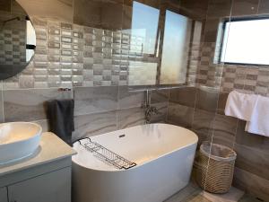 a bathroom with a white tub and a sink at Stunning gem by OR Tambo Airport in Benoni
