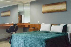 a bedroom with a bed with a green blanket and a mirror at BOMBONATO PALACE HOTEL in Uberaba