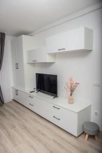 a white living room with a tv on a dresser at Maria's Premium Suite in Baia Mare