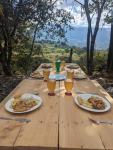a wooden table with plates of food and glasses of beer at Mamaterra Glamping in Macanal