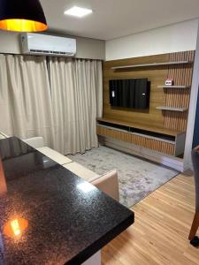 a living room with a table and a flat screen tv at Apartamento cuiaba climatizado in Cuiabá