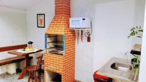 a kitchen with a brick oven with a sink at Villavera - Caragua Centro in Caraguatatuba