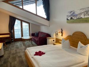 a bedroom with a bed with a red flower on it at Hotel Metzgerwirt in Kirchberg in Tirol