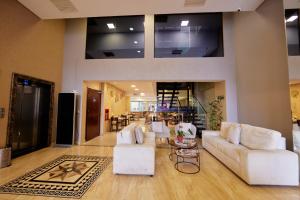 uma sala de estar com sofás brancos e uma mesa em Howard Johnson Ciudad del Este em Ciudad del Este